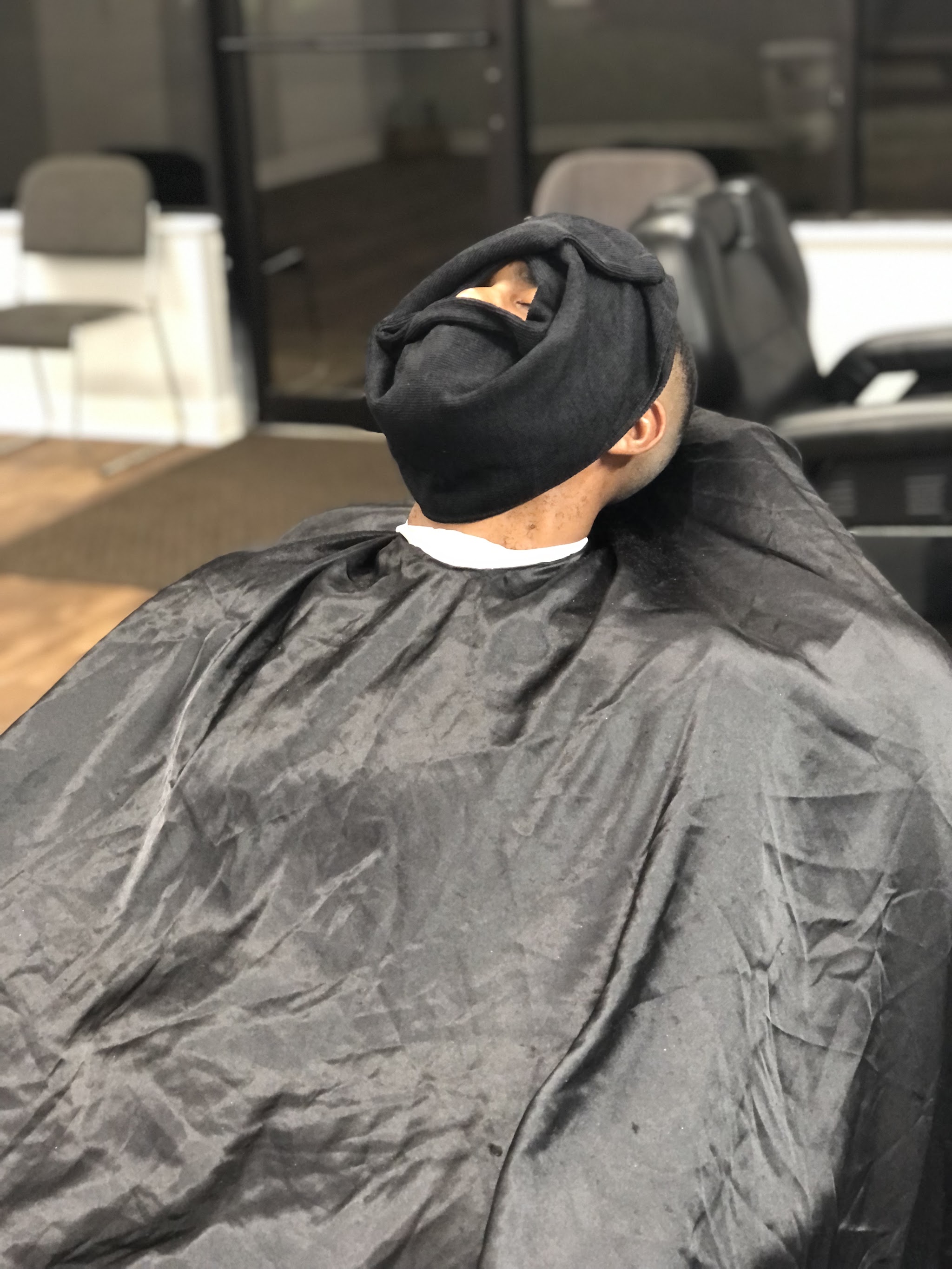 A client leaning back under a hot towel in our chair