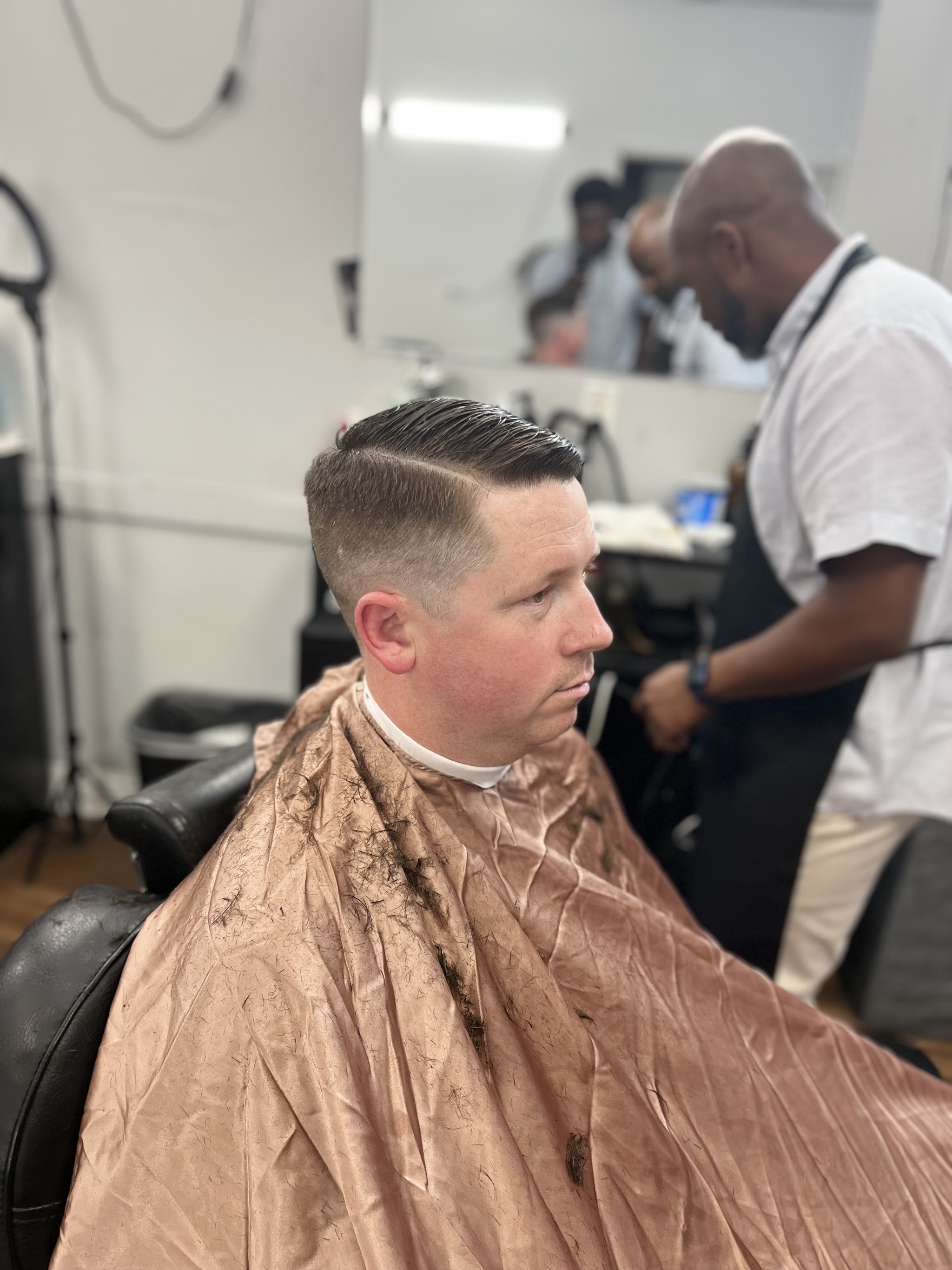 One of our barbers finishing a side part while a client looks on in the mirror