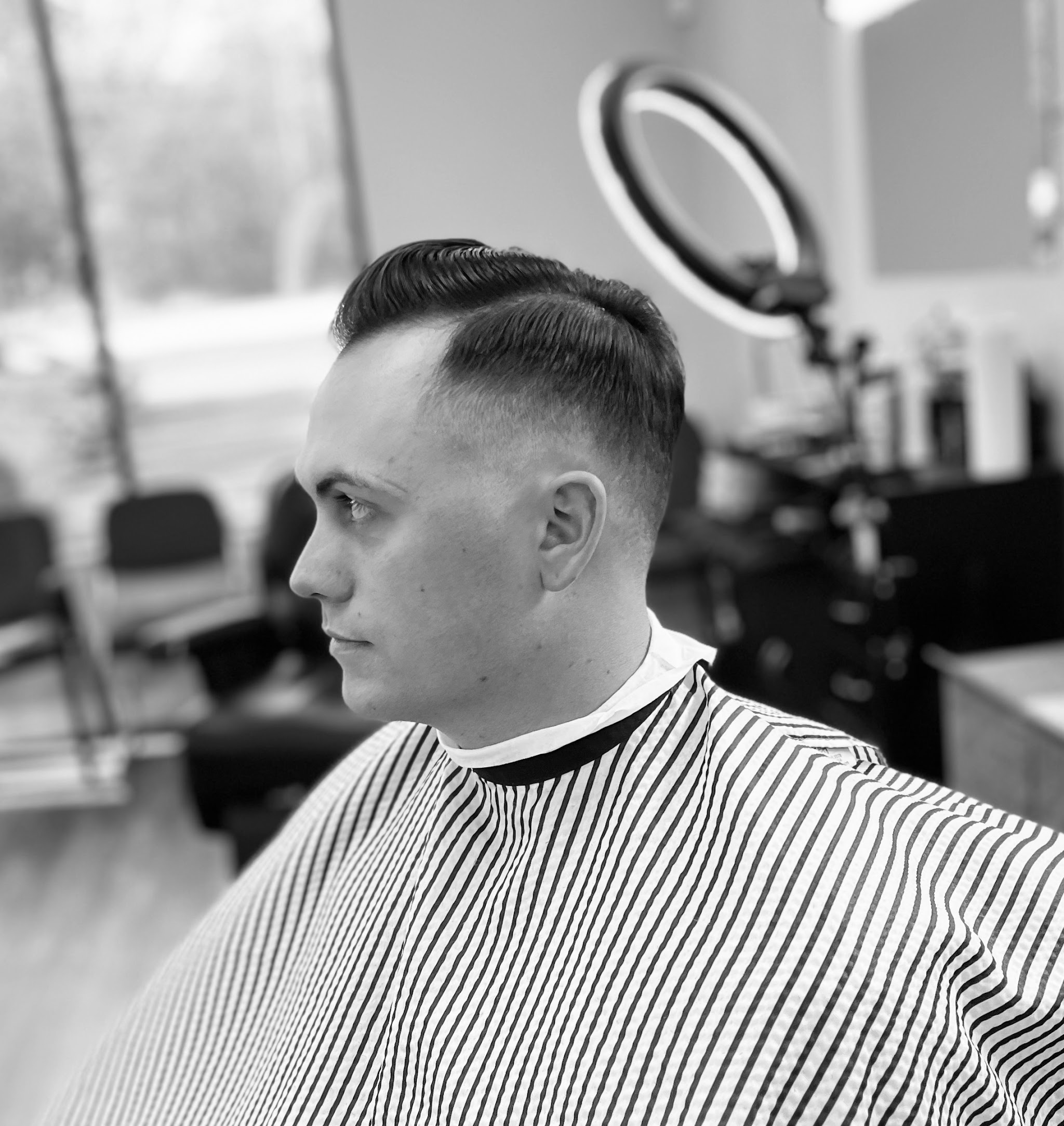 Classic side part with a sharp fade in a striped cape